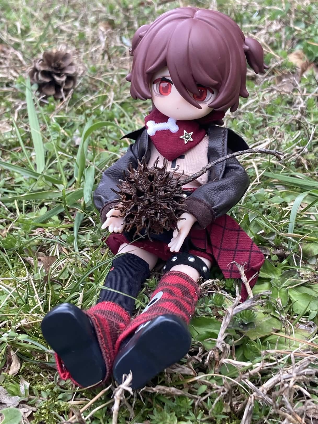 Elizabeth sitting outside holding a spiky seed pod.
