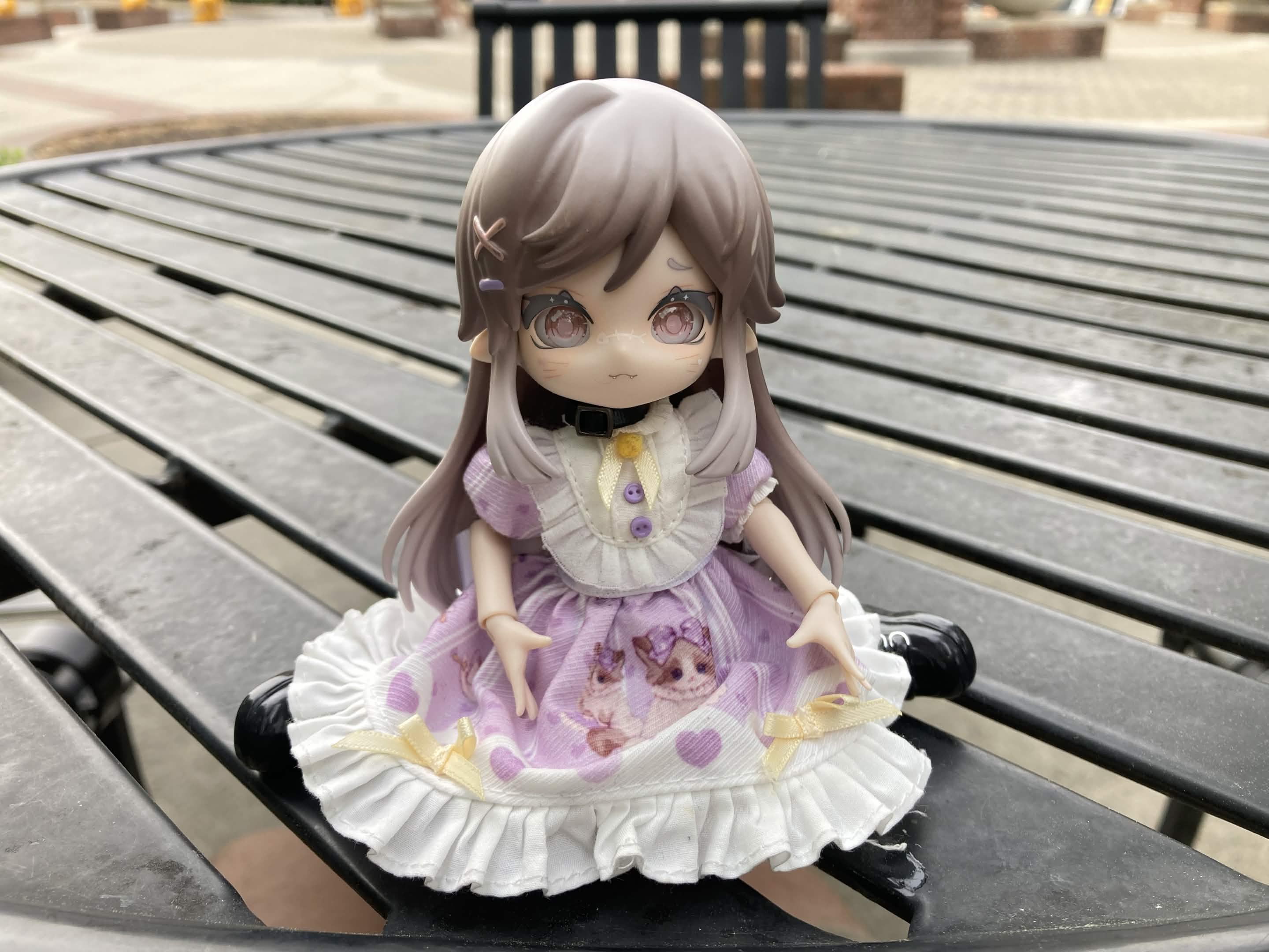 Teacup sits with her legs folded behind her on a table outside.