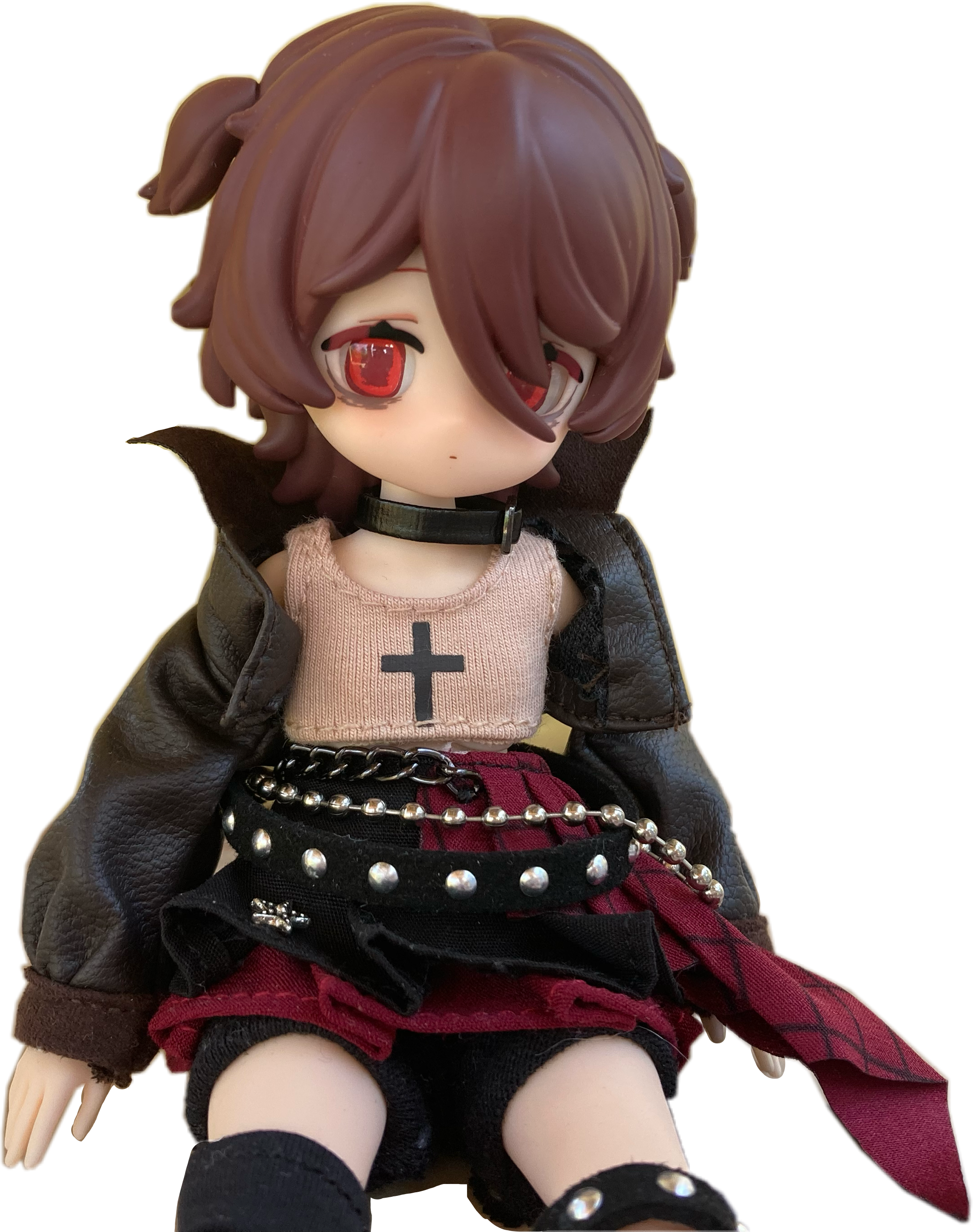Elizabeth has short, brown hair in two little ponytails. She has on a cropped faux leather jacket and a red plaid skirt. She has on three different belts.