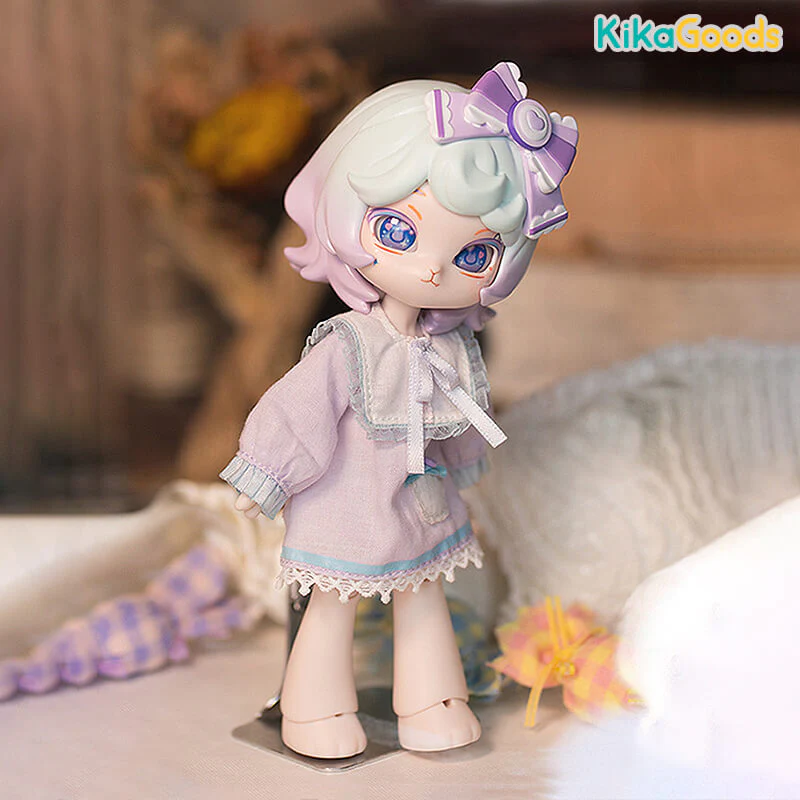 Taro is a small doll with short, purple and blue hair. She has a large, purple bow on her head. She wears a light purple nightgown and blue accents. Text at the top right reads: 'KikaGoods'.