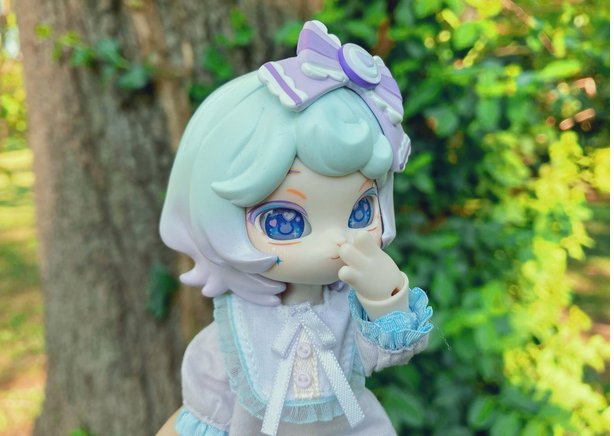 Taro with her paw over her mouth in front of a tree with vines growing up it.